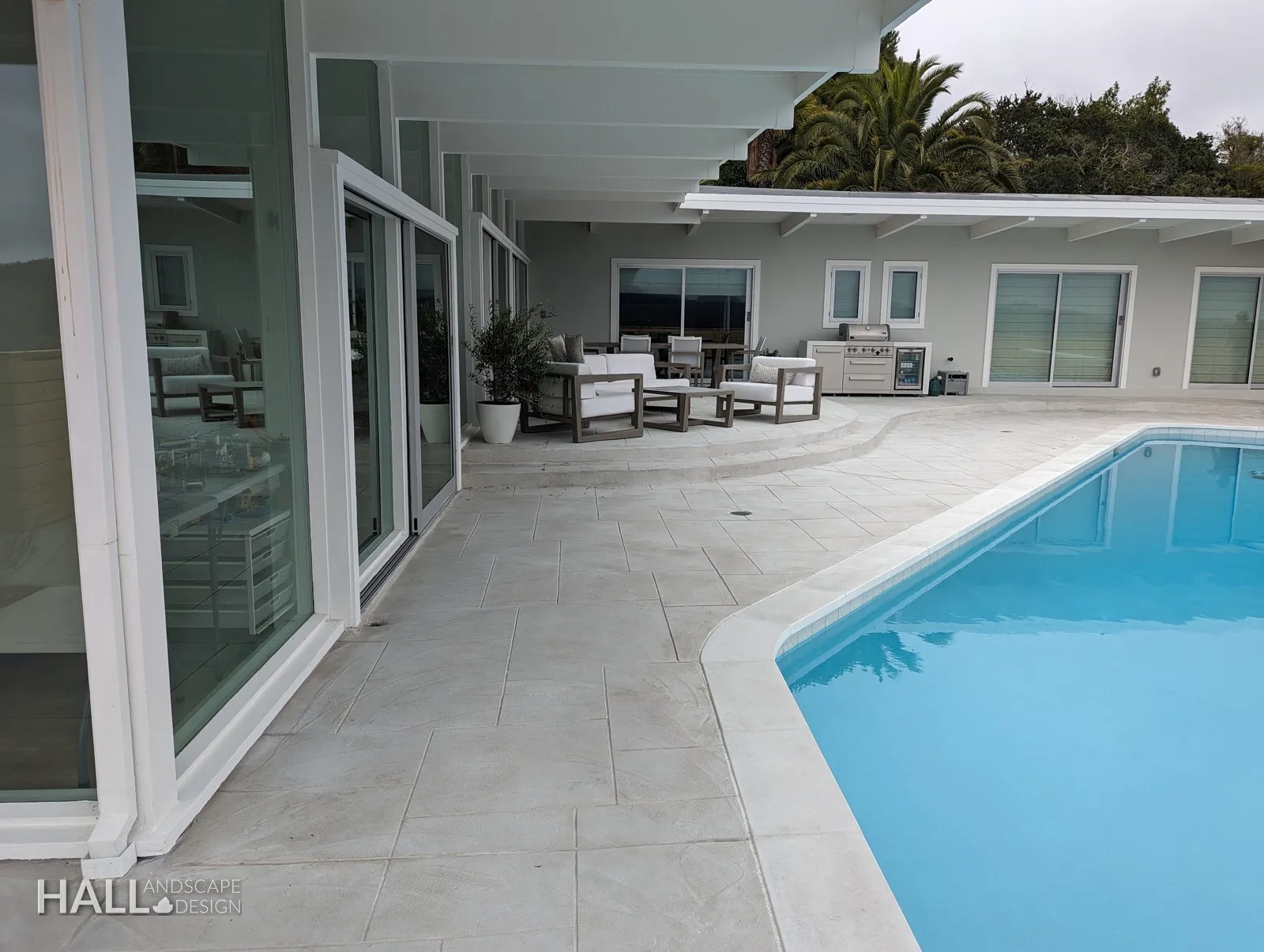 After — Bare concrete pool edge → new deck, pool & glass-wall lounge in Greenbrae