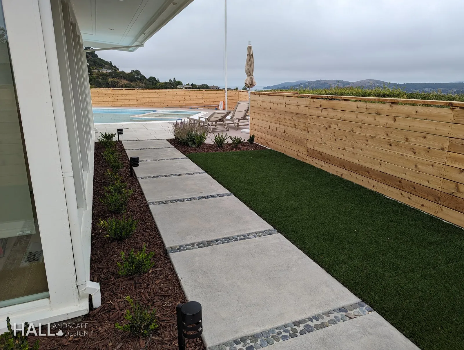 After — Overgrown side yard → turf panel, concrete pads & river-rock joints in Greenbrae