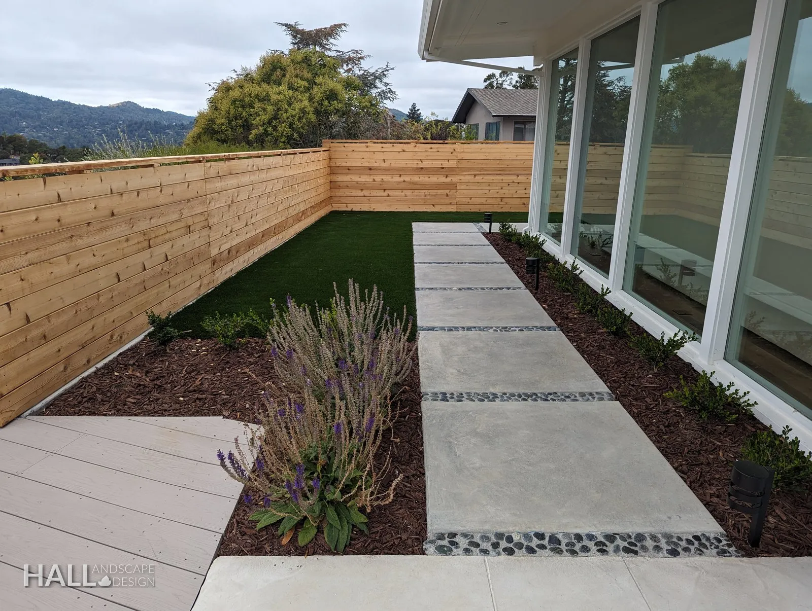 After — Cracked side path → turf, pavers & river rock along the glass wall in Greenbrae