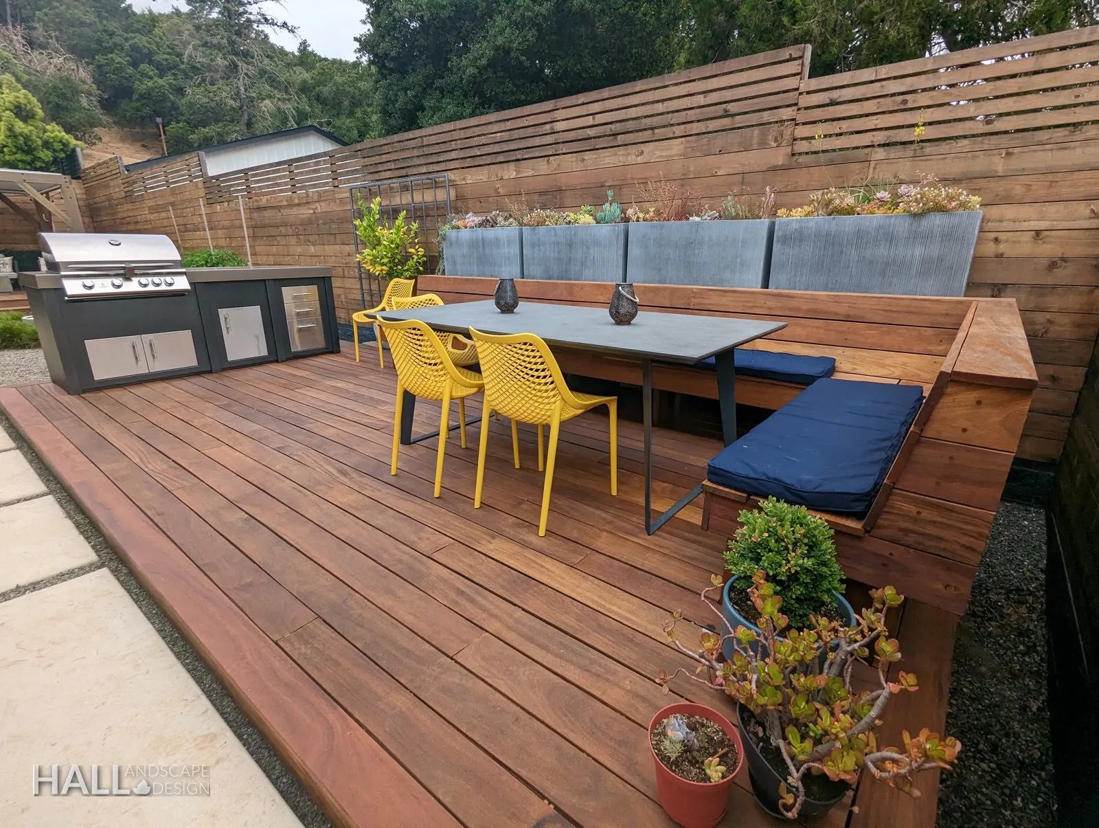 Dining deck: Built-in bench, outdoor kitchen, a long table. A finished Hall Landscape Design garden in Napa, California.