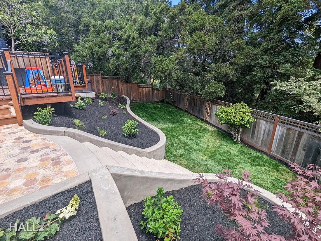 After — Weed-cloth slope below the deck → terraced lawn, planted beds & a curved wall in Sausalito