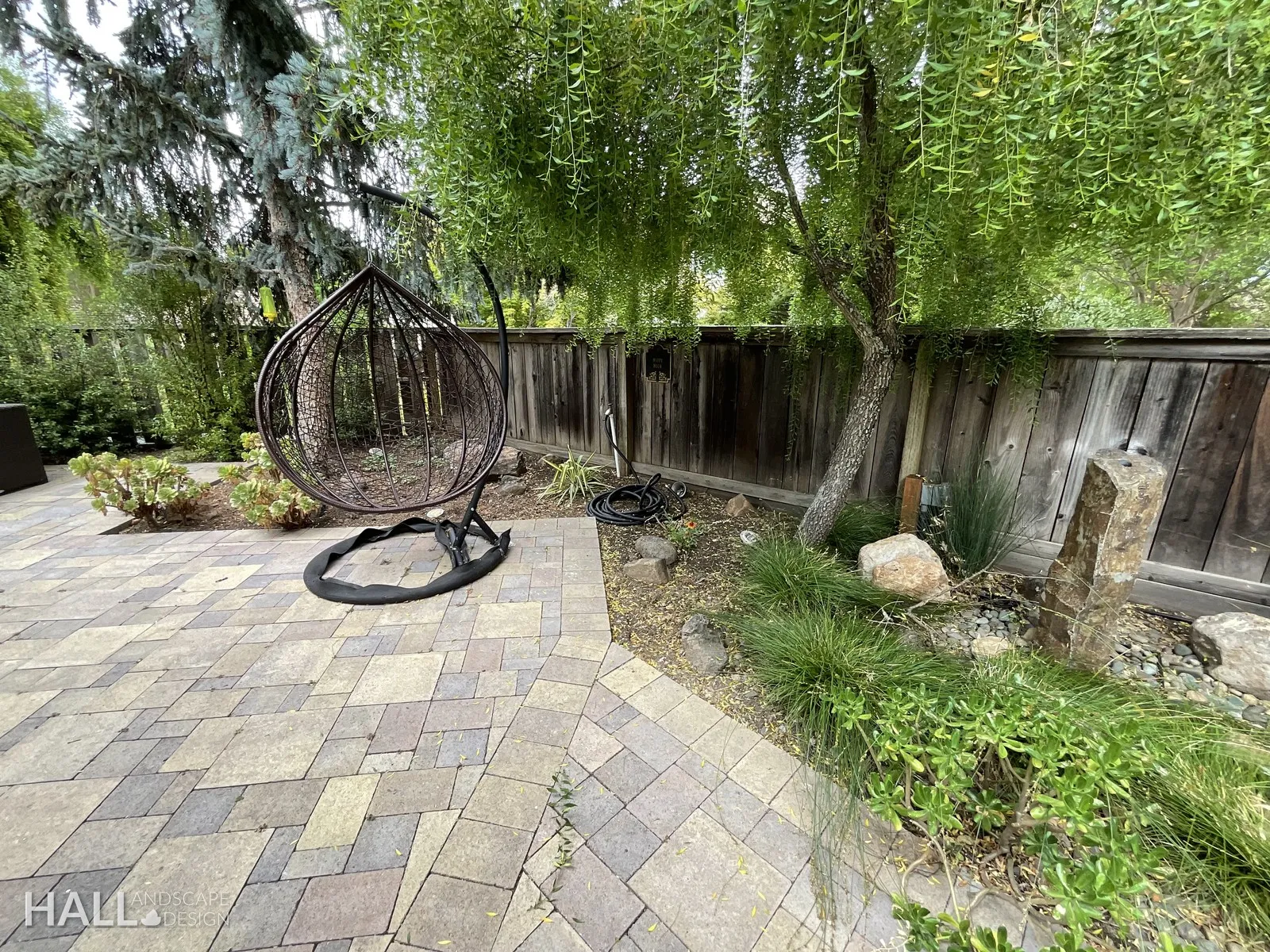After — Dead tree & dirt → paver nook with a hanging egg chair in Yountville