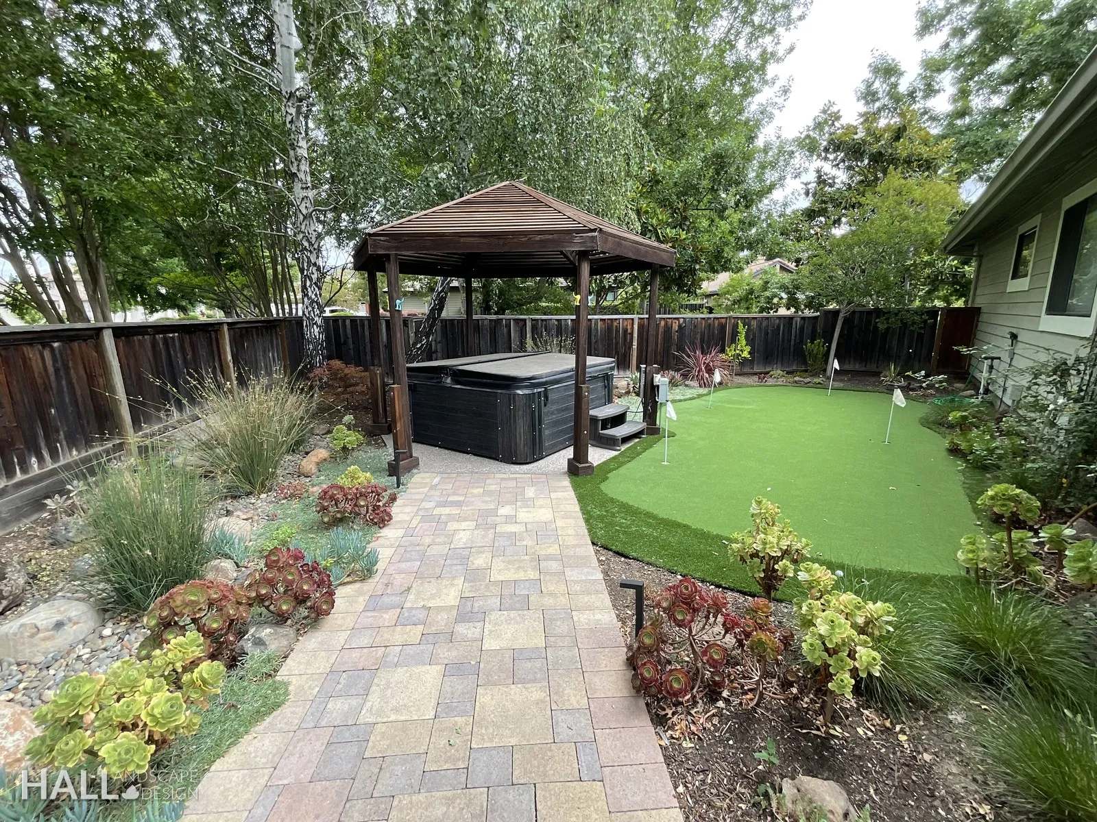 After — Old gazebo on gravel → hot tub, putting green & layered planting in Yountville