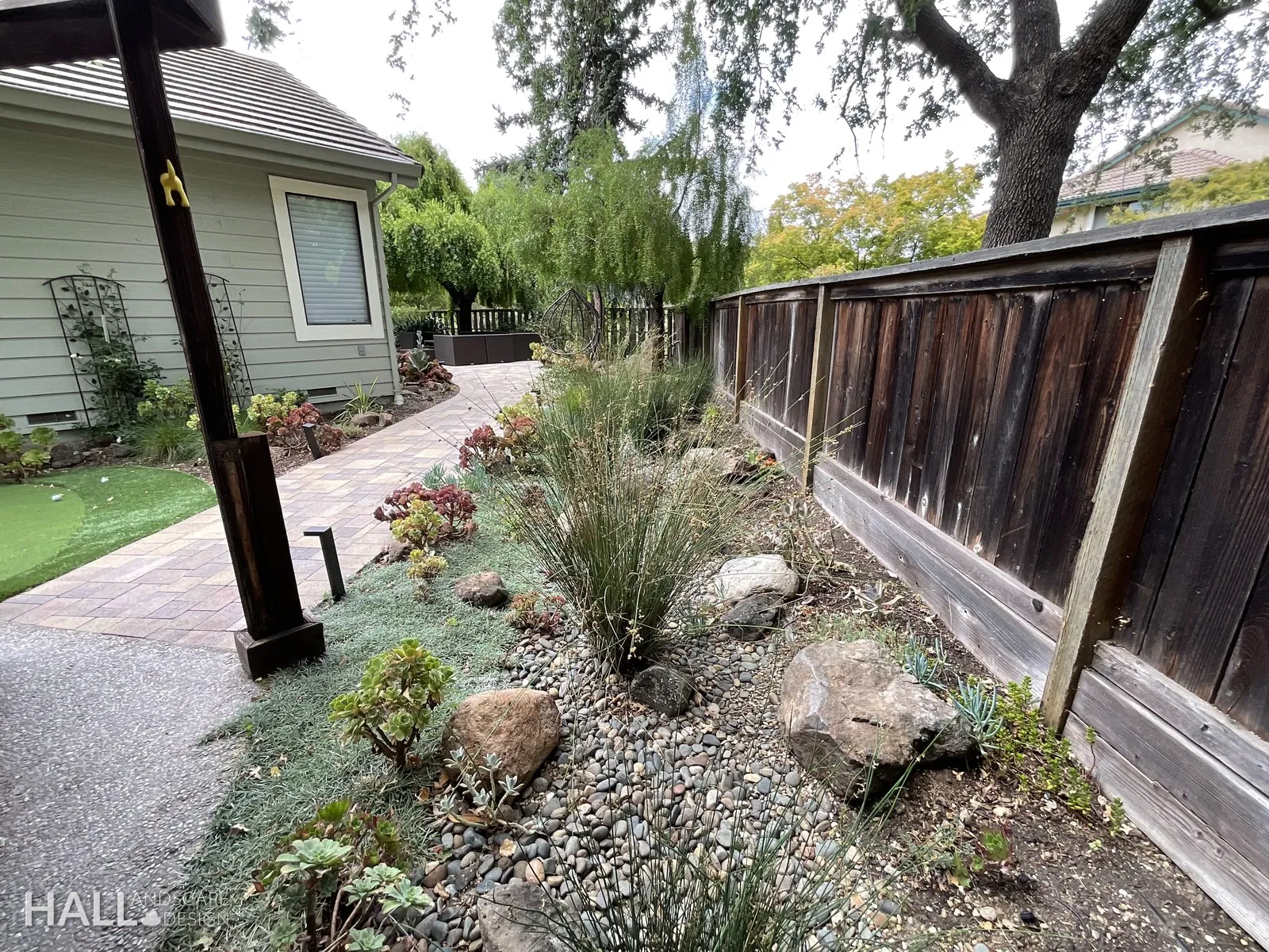After — Rock pile against the fence → boulder bed with grasses & a lit path in Yountville